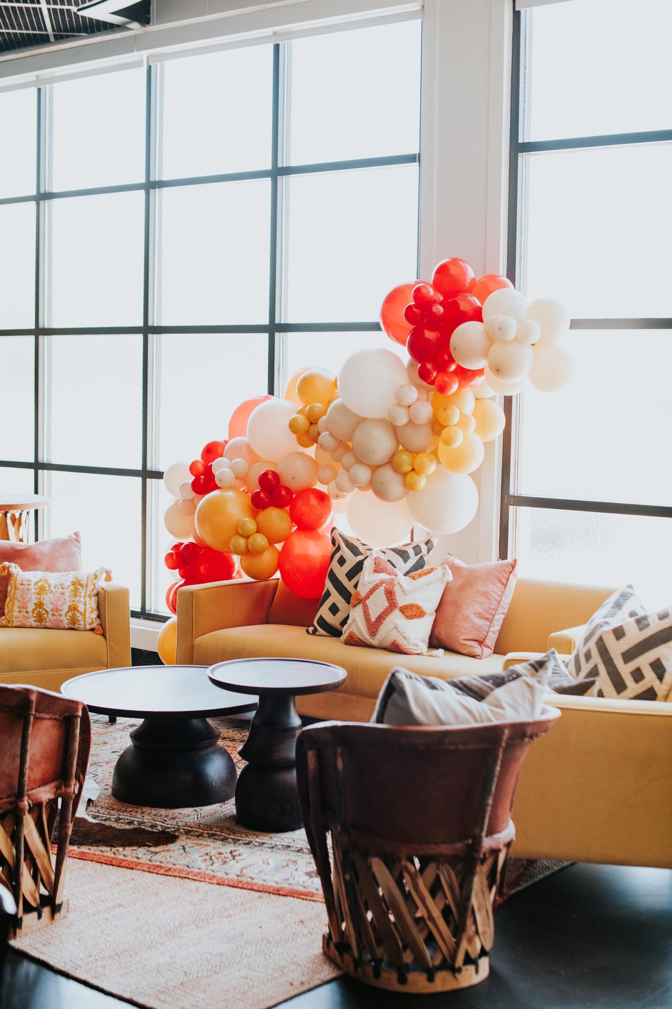 a velvet yellow sofa with a fun balloon arch flanked by rattan and leather chairs for a western baby shower