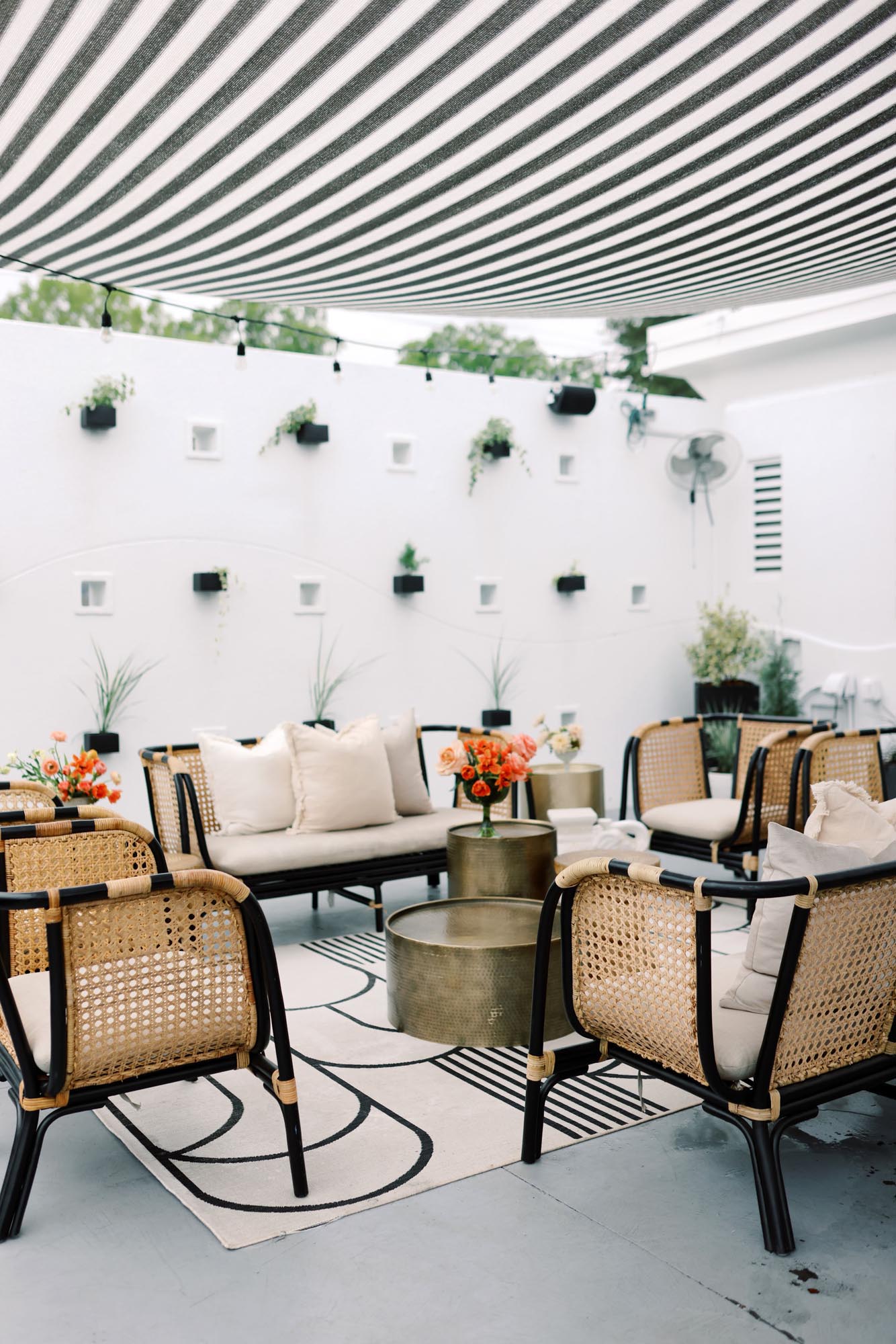 boho black caned outdoor lounge seating with gold cocktail tables and floral installations